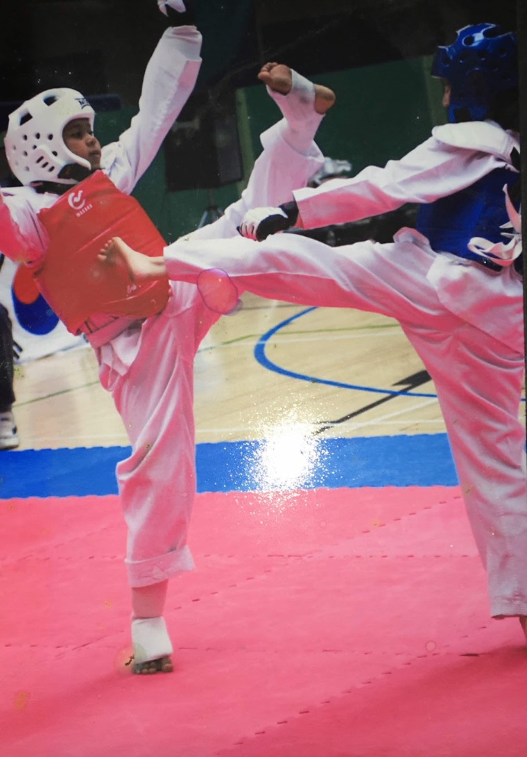A young Andrea throwing a high kick in competition
